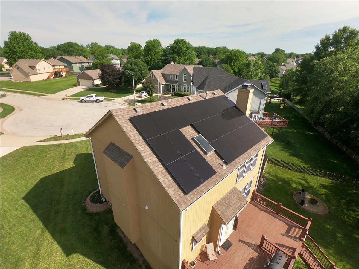 Drone view of a house with solar panels in a suburban neighborhood