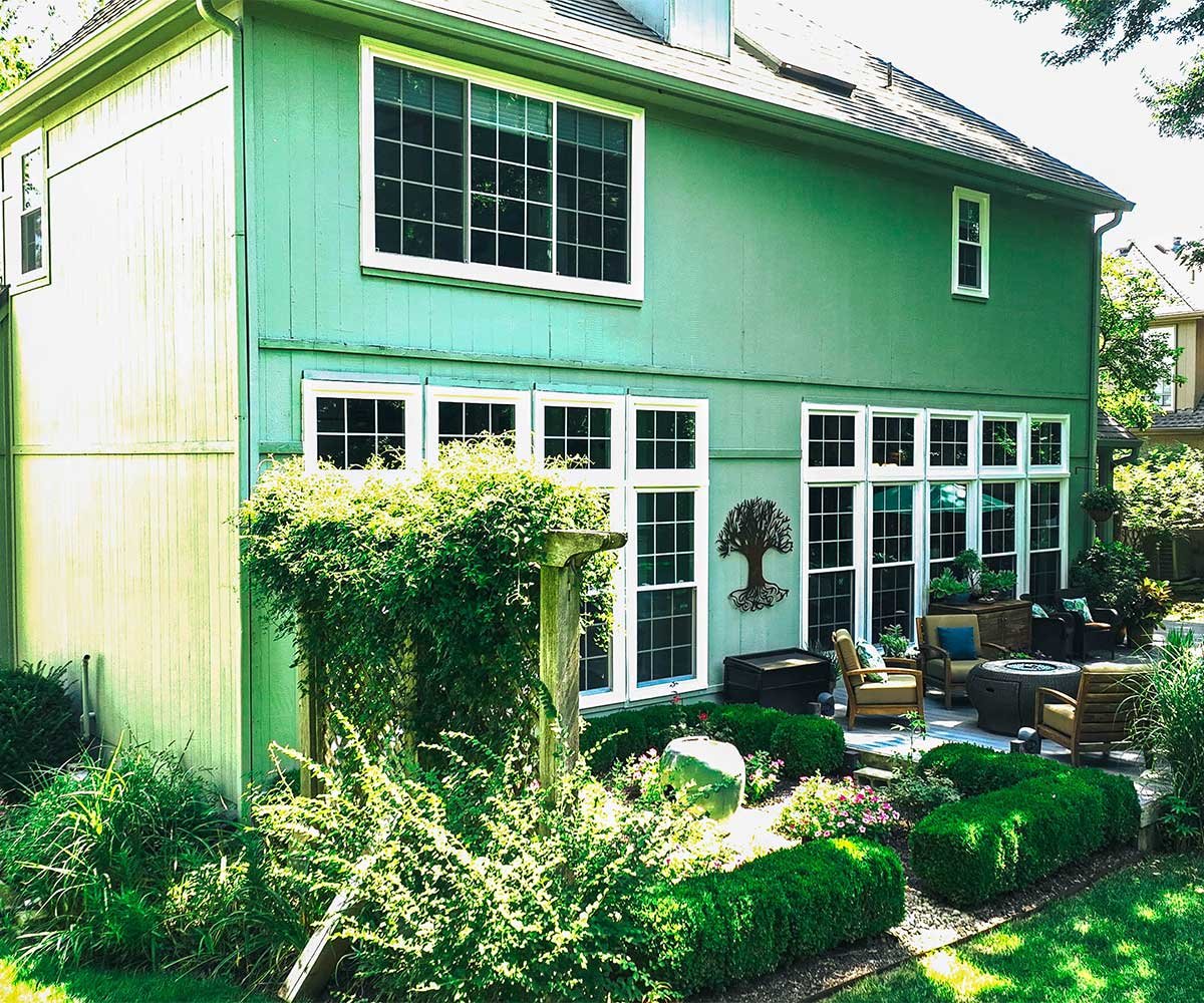 Green home with large replacement windows enhancing natural light and garden view