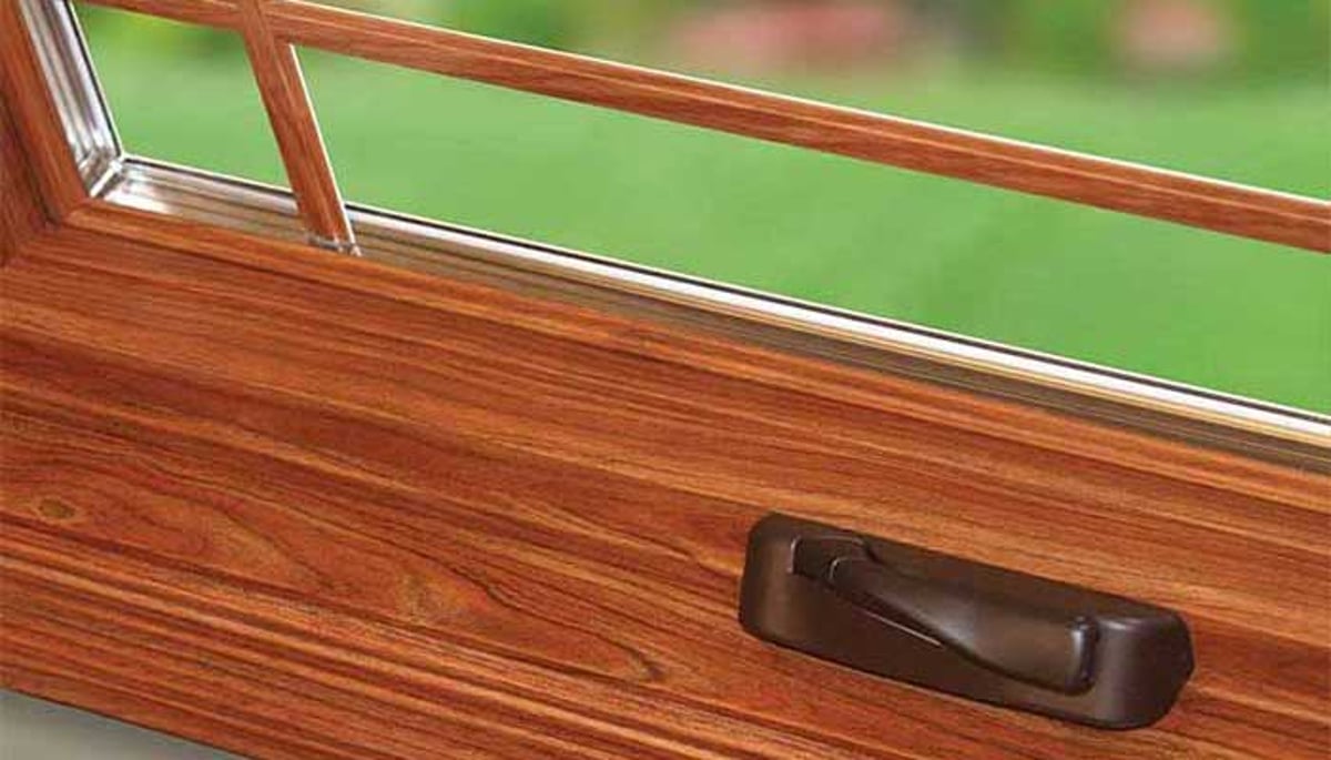 Close-up of casement window crank handle with wooden frame trim